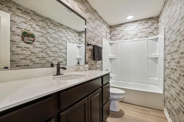 full bathroom featuring brick wall, visible vents, vanity, and toilet