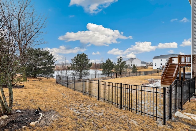 view of yard featuring a water view, fence, and stairway