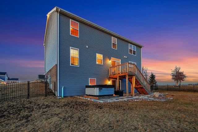 rear view of property with a hot tub, stairway, a gate, fence, and a deck