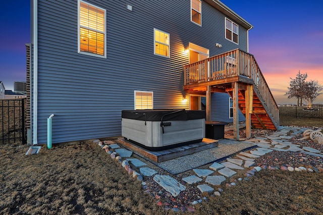 back of house featuring a deck, stairway, fence, and a hot tub