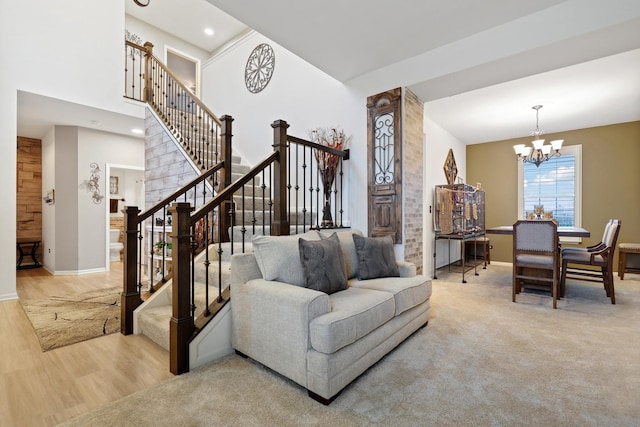 carpeted living room featuring a notable chandelier, wood finished floors, a towering ceiling, baseboards, and stairway