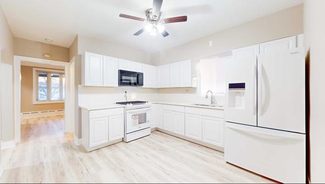 kitchen featuring white appliances, light wood finished floors, light countertops, white cabinetry, and a sink