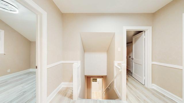 corridor featuring light wood-type flooring, baseboards, and an upstairs landing