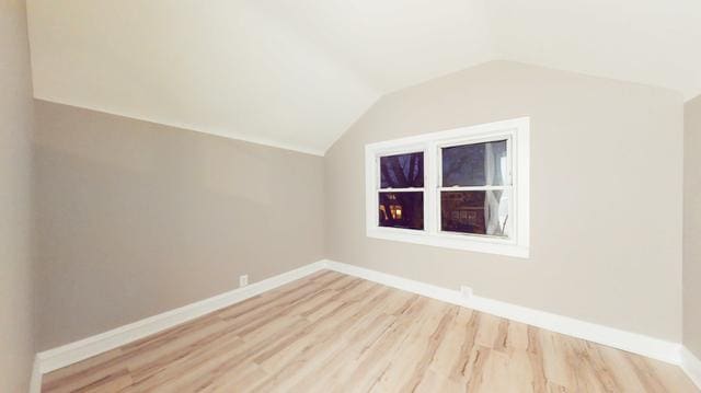 additional living space with vaulted ceiling, light wood-type flooring, and baseboards