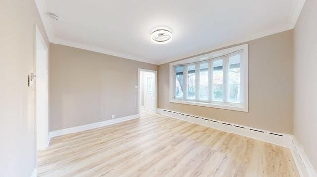 empty room featuring light wood-style flooring, a baseboard heating unit, baseboards, and ornamental molding