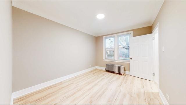 unfurnished room featuring radiator, light wood-type flooring, and baseboards