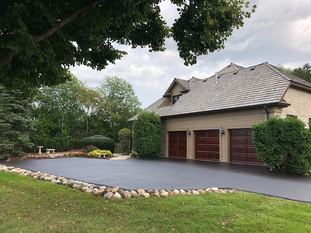 view of property exterior with driveway, an attached garage, and a lawn