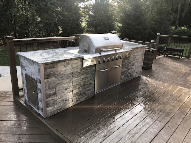 deck with an outdoor kitchen and a grill