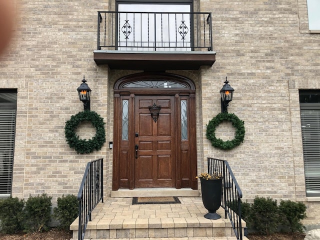 entrance to property featuring brick siding and a balcony