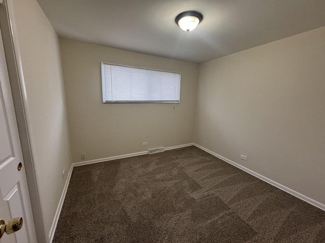 empty room with baseboards, visible vents, and dark colored carpet