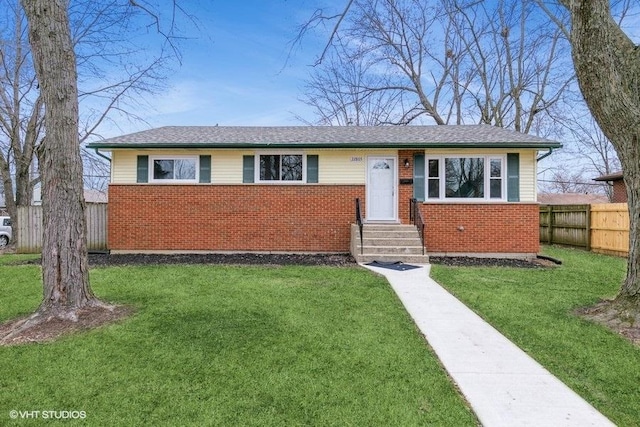 ranch-style house with a front yard, fence, and brick siding