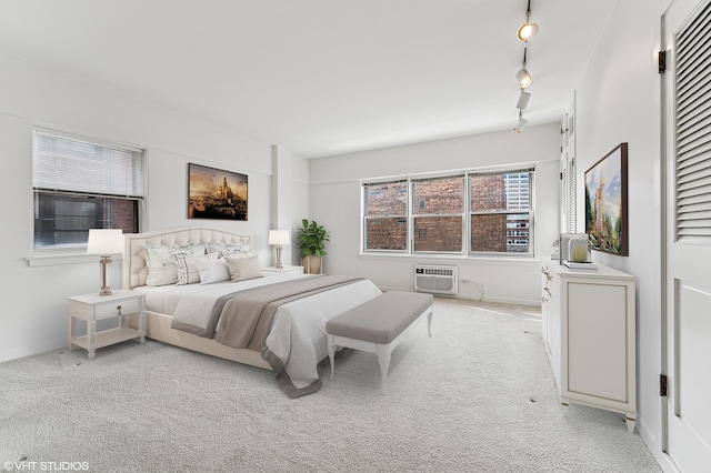 bedroom featuring light carpet, a wall unit AC, and track lighting