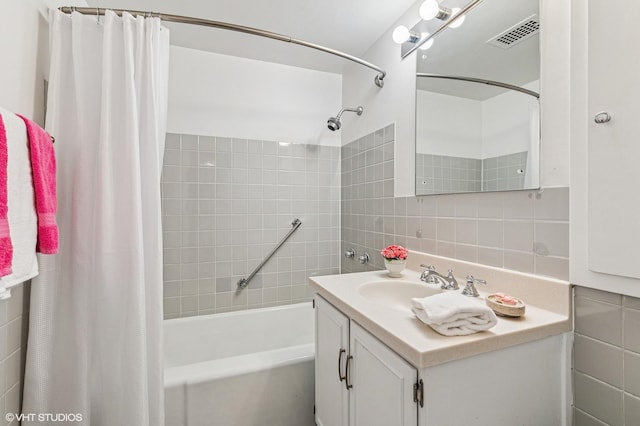 full bathroom featuring shower / bath combo, visible vents, decorative backsplash, vanity, and tile walls