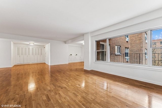 unfurnished living room with baseboards and wood finished floors