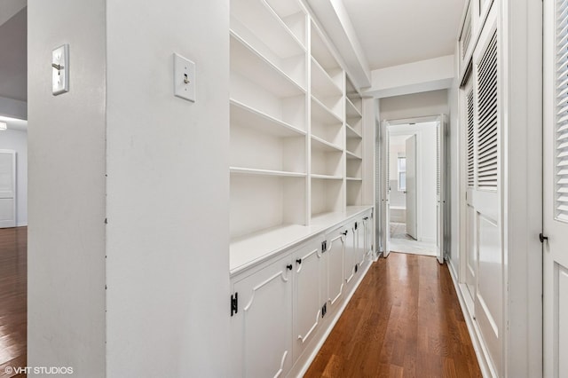 hallway featuring built in shelves and dark wood-type flooring