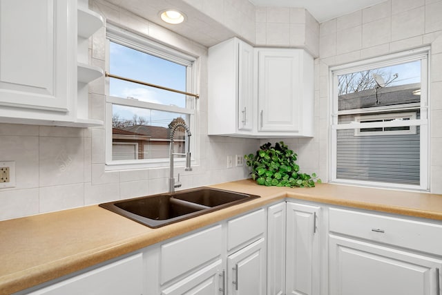 kitchen featuring decorative backsplash, white cabinets, a sink, and light countertops