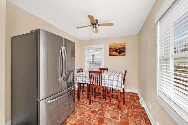 dining area featuring ceiling fan, stone finish floor, and baseboards