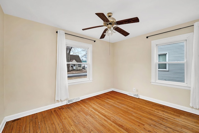 spare room with visible vents, baseboards, and wood finished floors