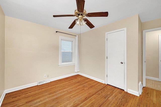 unfurnished bedroom featuring a ceiling fan, visible vents, light wood-style flooring, and baseboards