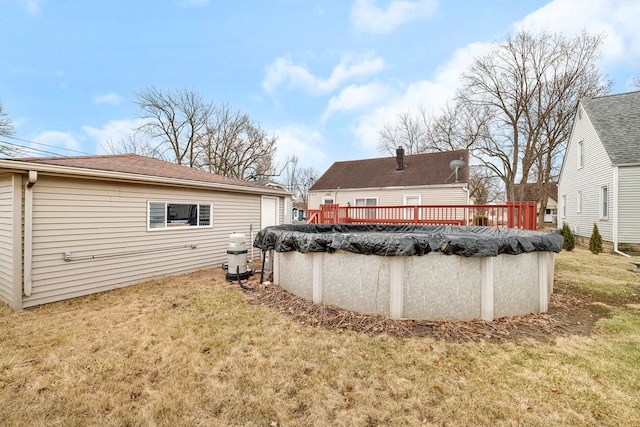 rear view of house with a covered pool, a deck, and a lawn