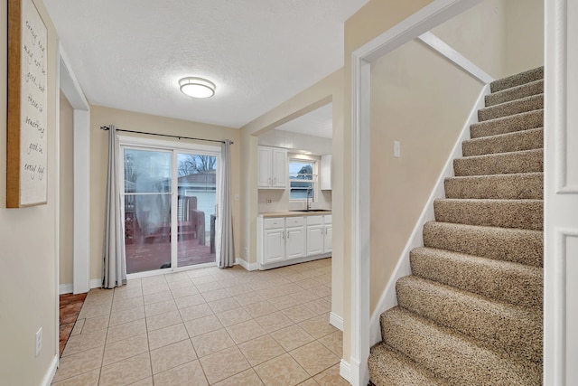 staircase featuring a textured ceiling, baseboards, and tile patterned floors