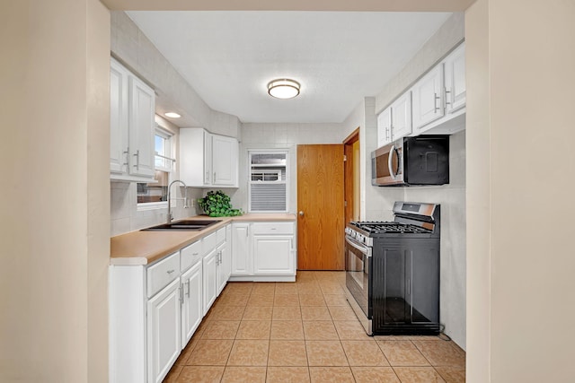 kitchen featuring white cabinets, a sink, stainless steel appliances, and light countertops