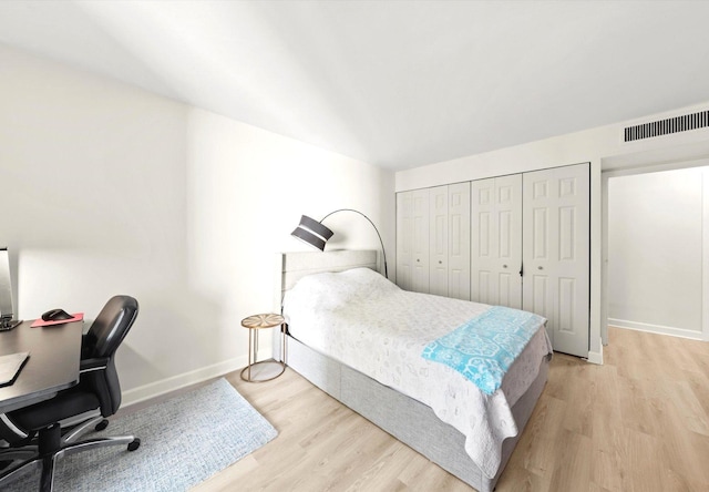 bedroom with a closet, light wood-type flooring, visible vents, and baseboards