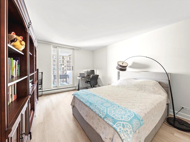 bedroom featuring light wood-style floors, a baseboard radiator, and baseboards