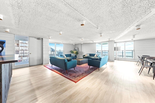 living room with expansive windows, a textured ceiling, and light wood finished floors