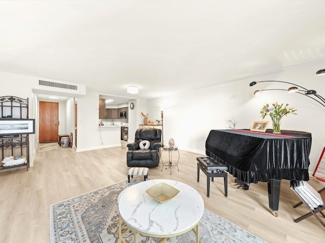 living area with light wood-style flooring, visible vents, and baseboards