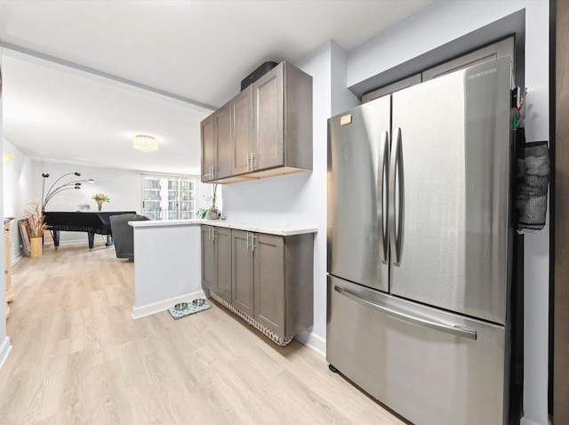 kitchen with light countertops, light wood-style flooring, freestanding refrigerator, and dark brown cabinetry