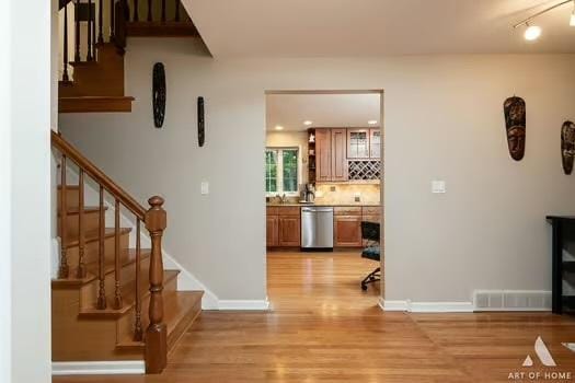 interior space with stairs, light wood-type flooring, visible vents, and baseboards