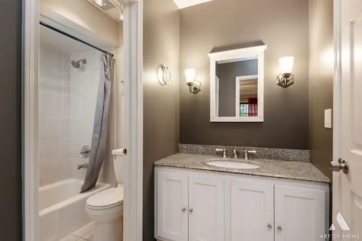 bathroom with toilet, shower / bath combo with shower curtain, and vanity