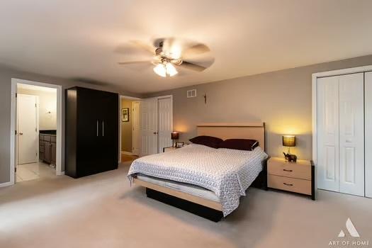 bedroom with ceiling fan, connected bathroom, light carpet, visible vents, and a closet