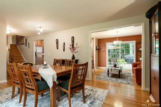 dining space featuring light wood-type flooring, baseboards, and stairs