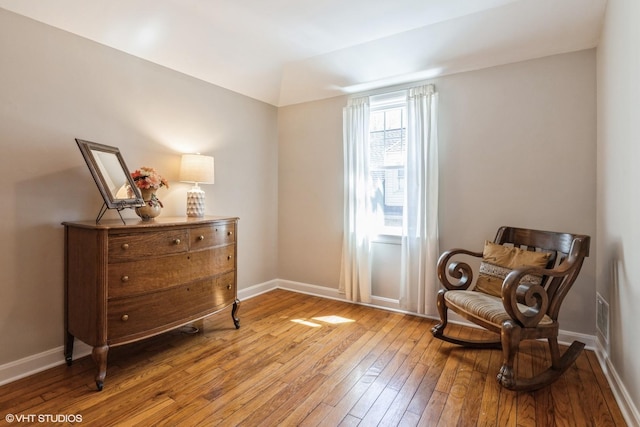 living area featuring visible vents, light wood-style flooring, and baseboards