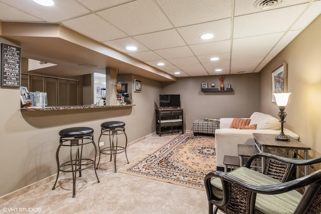 living room featuring baseboards, visible vents, a drop ceiling, and recessed lighting