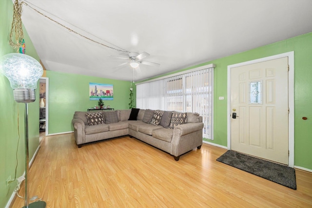 living room featuring light wood finished floors, baseboards, and a ceiling fan