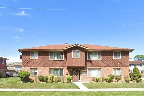 view of property featuring brick siding and a front lawn