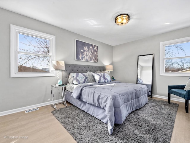 bedroom featuring baseboards, visible vents, and wood finished floors