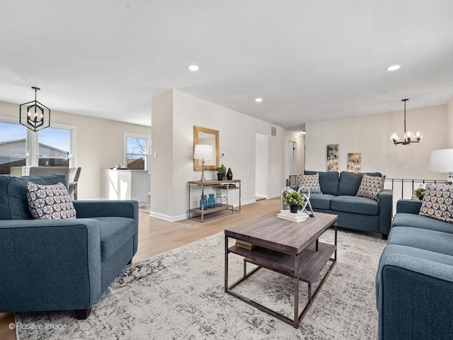 living room featuring baseboards, recessed lighting, light wood-style flooring, and an inviting chandelier