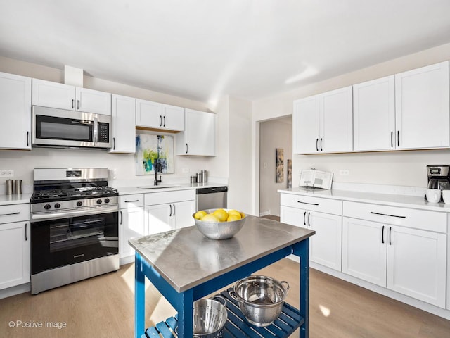 kitchen featuring stainless steel appliances, light countertops, a sink, and white cabinetry