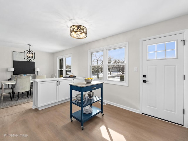 entrance foyer featuring a chandelier, baseboards, and light wood finished floors