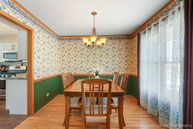 dining space featuring a chandelier, light wood-style flooring, and wallpapered walls