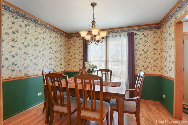 dining room with a wainscoted wall, a chandelier, wood finished floors, and wallpapered walls