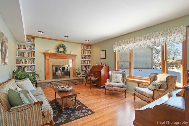 living room featuring built in features, wood finished floors, and a glass covered fireplace