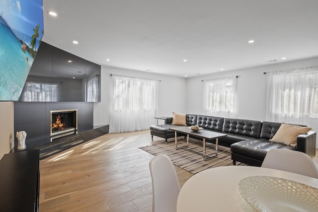 living room featuring plenty of natural light, a fireplace, recessed lighting, and hardwood / wood-style flooring