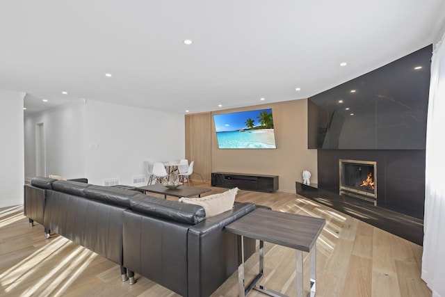 living area featuring recessed lighting, a large fireplace, and wood finished floors