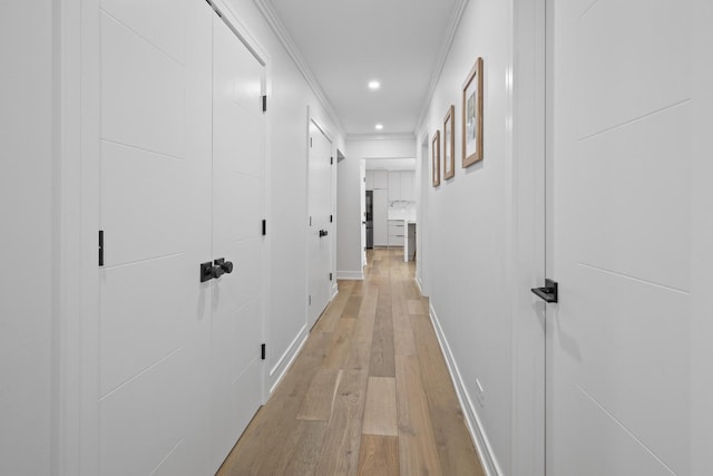 hallway featuring baseboards, light wood finished floors, recessed lighting, and crown molding