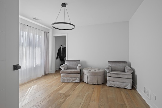 living area with hardwood / wood-style flooring, baseboards, and visible vents